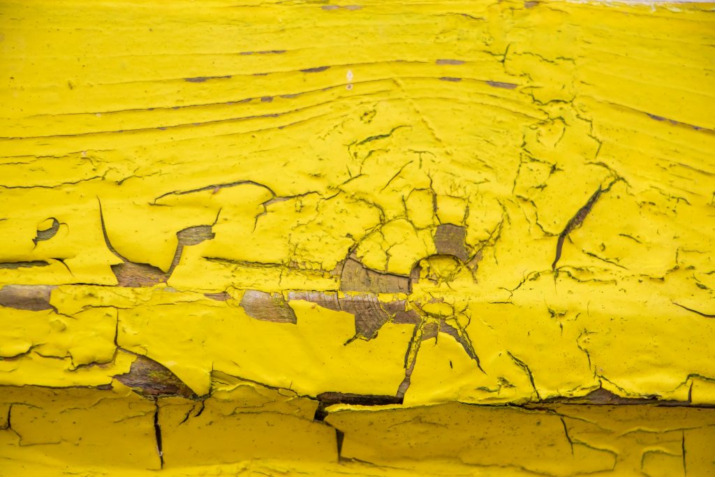 Background from old yellow boards. Close-up of cracks and chips in the paint.